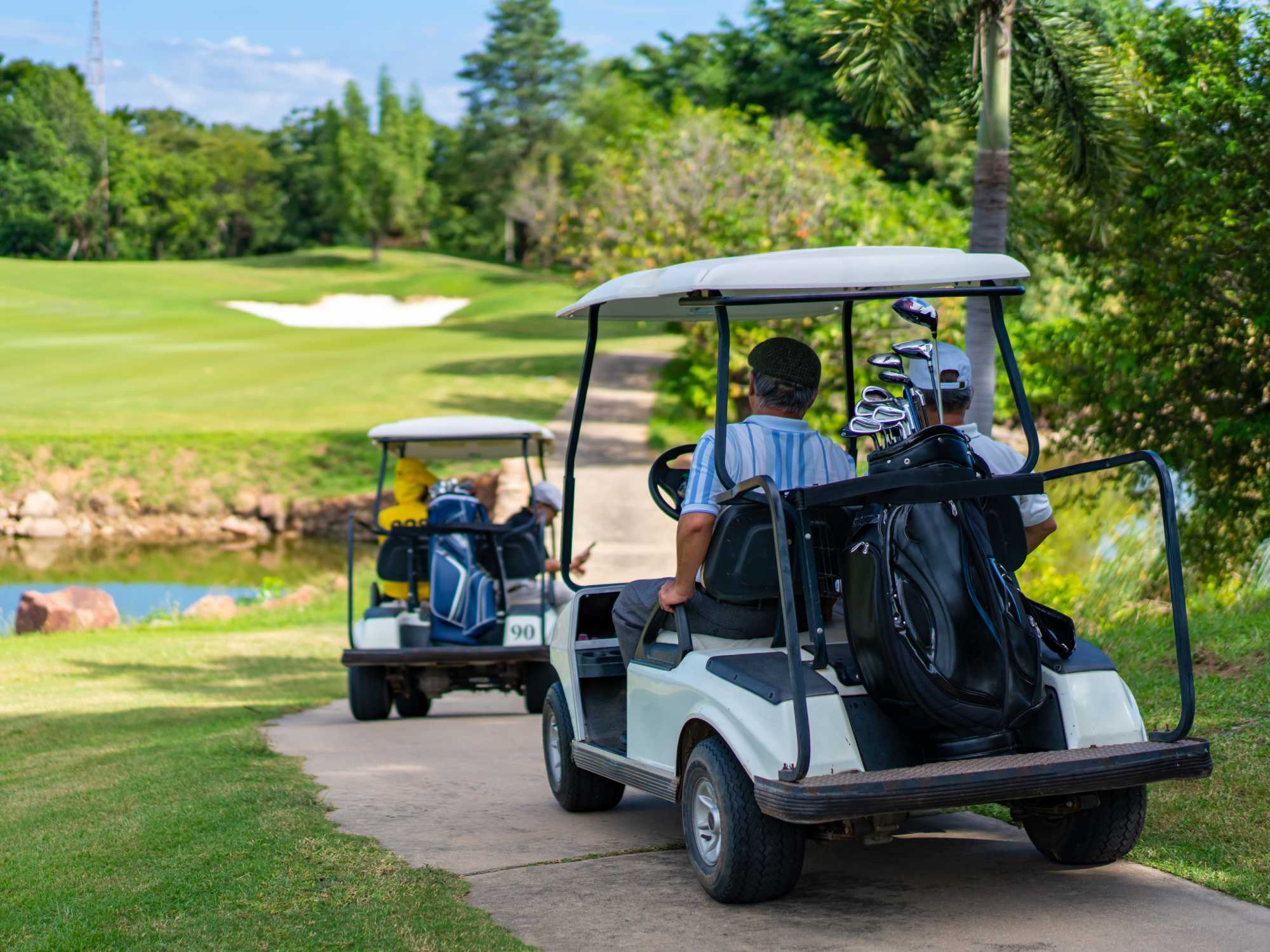 A group of daytime golfers enjoying a hot summer day on the course, cruising on their golf carts.